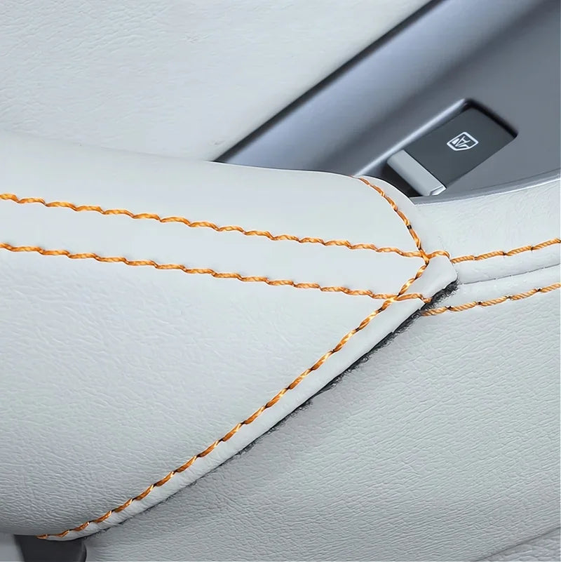 Close-up of premium white leather car seat upholstery with distinctive orange contrast stitching.