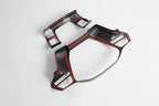 Black carbon fiber car interior trim with striking red accents.