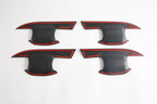 Four black matte door sill protector plates with distinctive red trim accents.