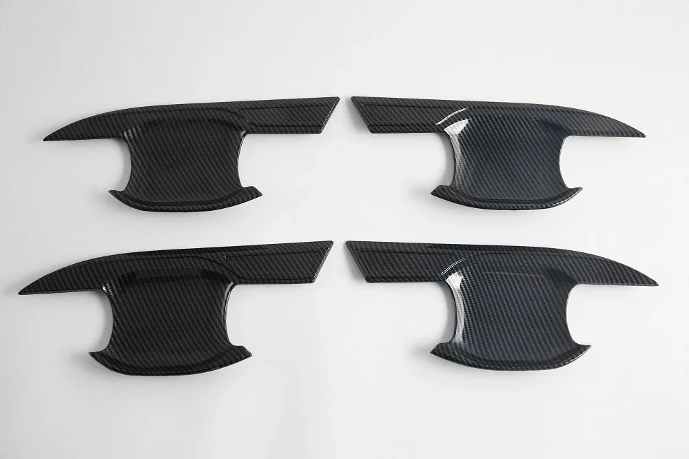 Set of four black carbon fiber texture interior trim panels for car door protection.