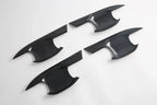 Four sleek black carbon fiber interior trim pieces with a glossy finish.