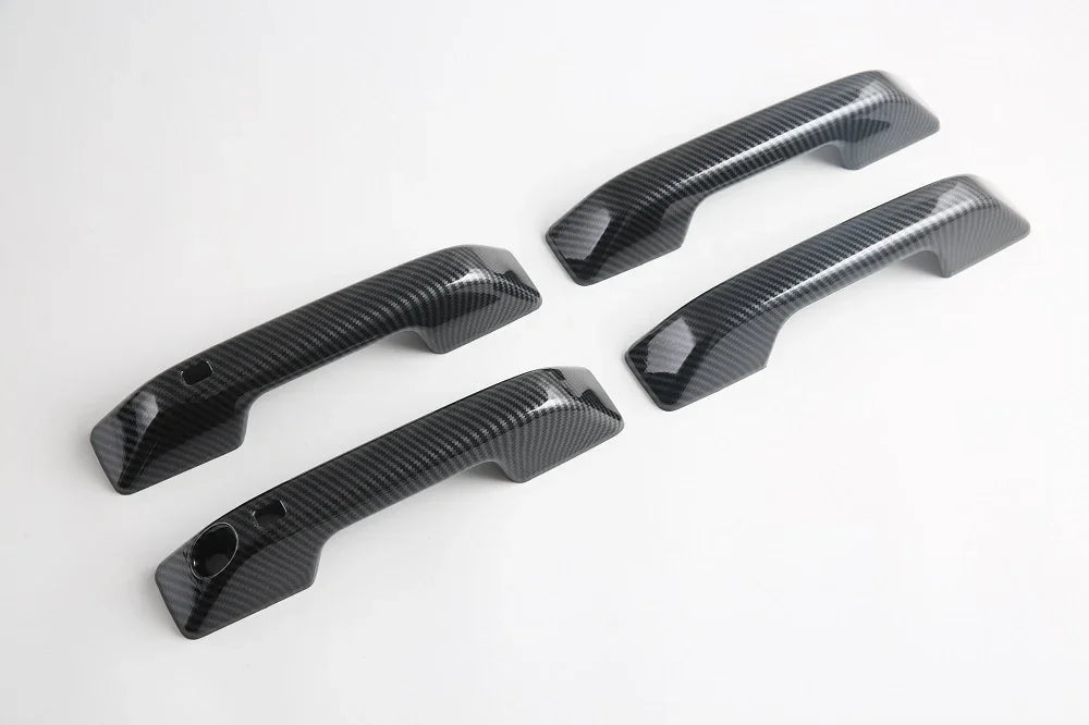 Four black carbon fiber textured car door handle covers for premium protection and style.