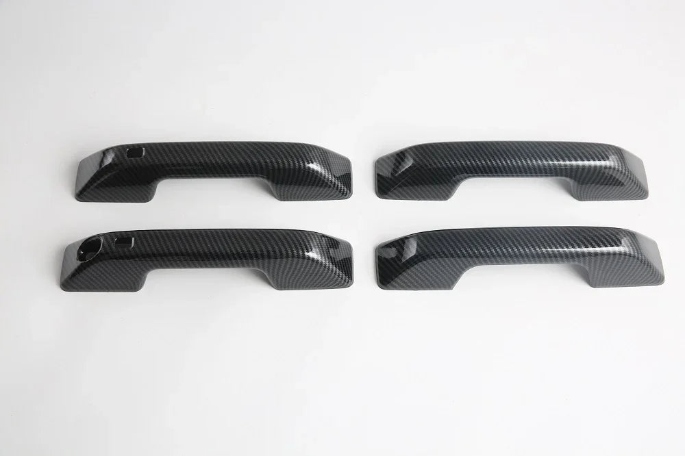 Set of four black carbon fiber texture car door handle covers for premium protection.