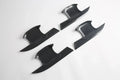 Four black carbon fiber door trim covers with a glossy textured finish.