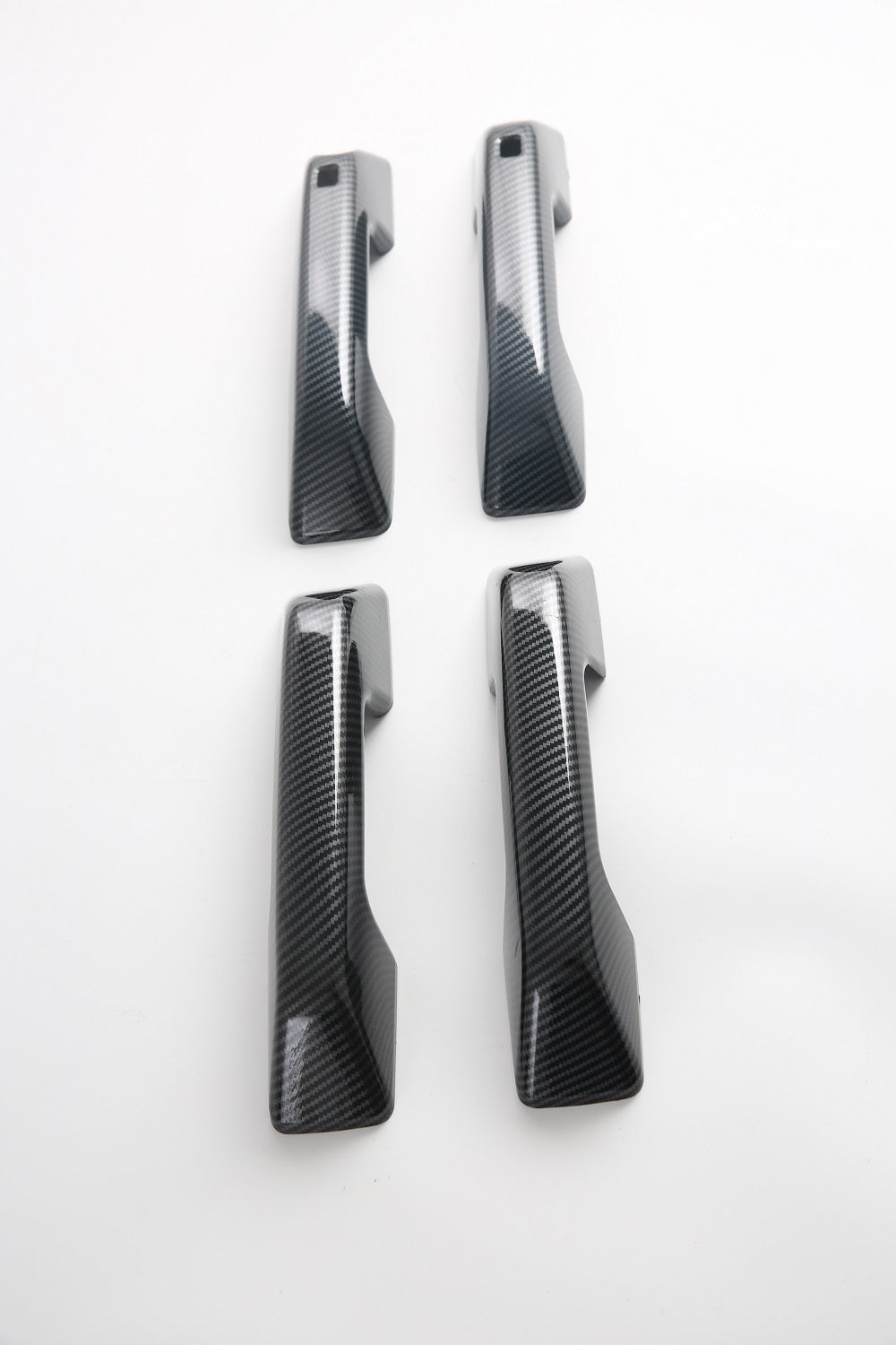 Set of four black carbon fiber texture door handle covers for automotive interior protection.
