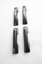 Set of four black carbon fiber texture door handle covers for automotive interior protection.