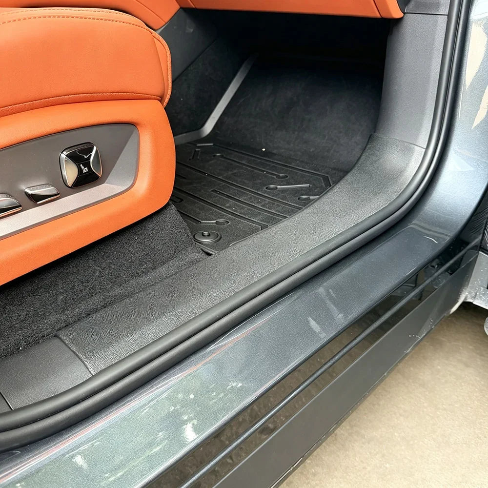 Interior view of a car showing orange leather seats and black heavy-duty floor mats.