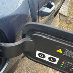 Black matte protective cover for BYD electric vehicle charging port with safety warning labels.