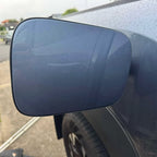 Matte grey side mirror housing on a dark blue car with water droplets.