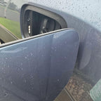 Close-up of a grey car door handle area with water droplets on the metallic surface.
