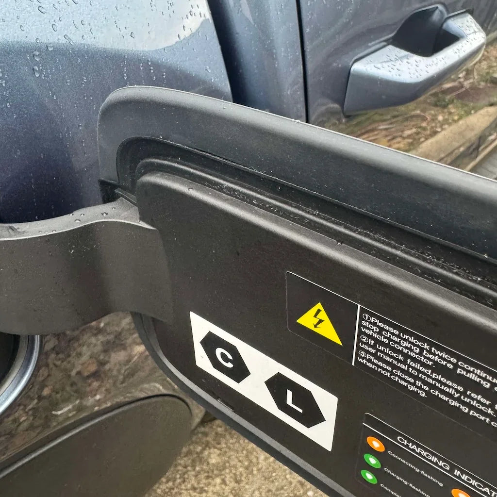 Black durable protective cover for BYD electric vehicle charging port with warning labels.