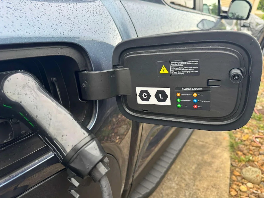 Close-up of a black BYD electric vehicle charging port cover with a colorful LED charging indicator.
