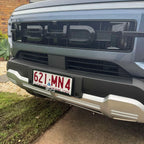 Glossy black BYD front grille with bold lettering on a grey vehicle bumper.