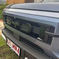 Glossy black BYD emblem and textured grille on a grey BYD vehicle front bumper.