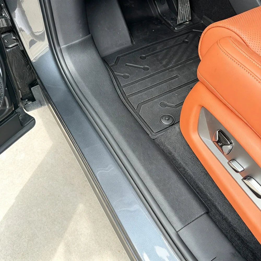 Black heavy-duty TPE floor mats protecting the interior of a vehicle with orange leather seats.