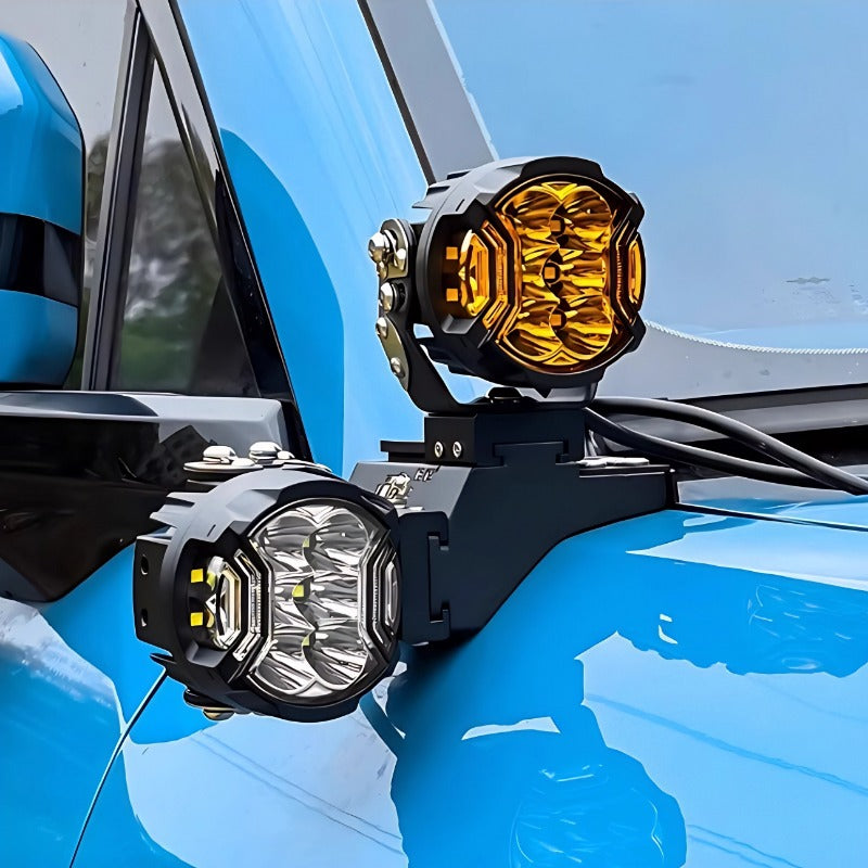 Black metal mounted amber and clear LED auxiliary driving lights on a blue vehicle.