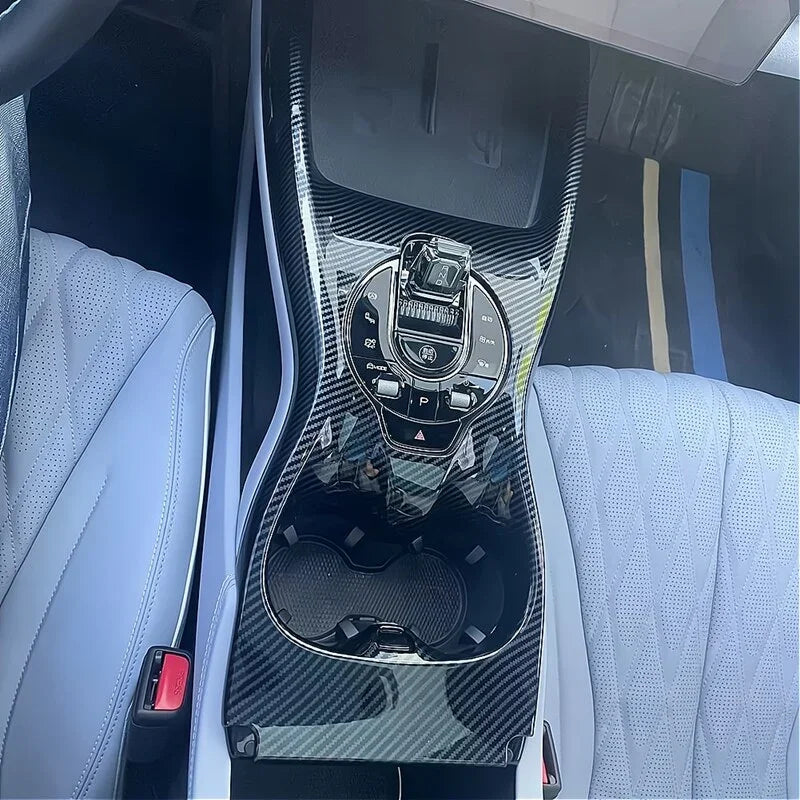 Carbon fiber texture center console trim in a modern car interior with light grey leather seats.