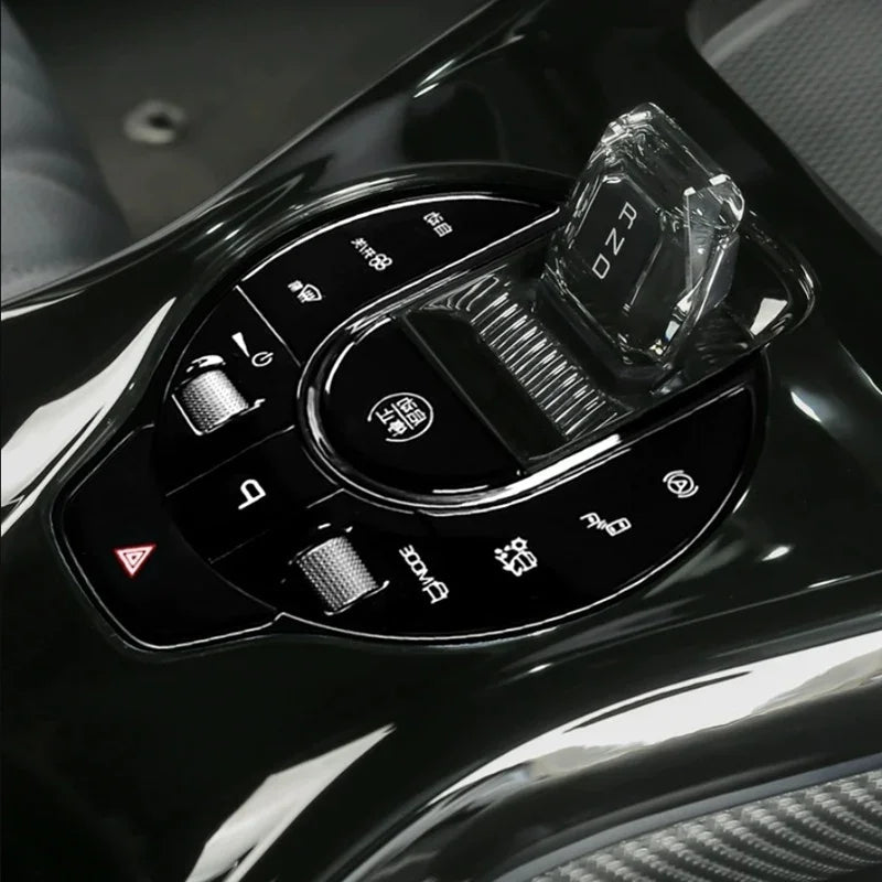 Close-up of a sleek black car gear shifter with a transparent crystal knob and illuminated icons.