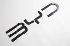 Black carbon fiber patterned BYD emblem badge for car exterior customization.