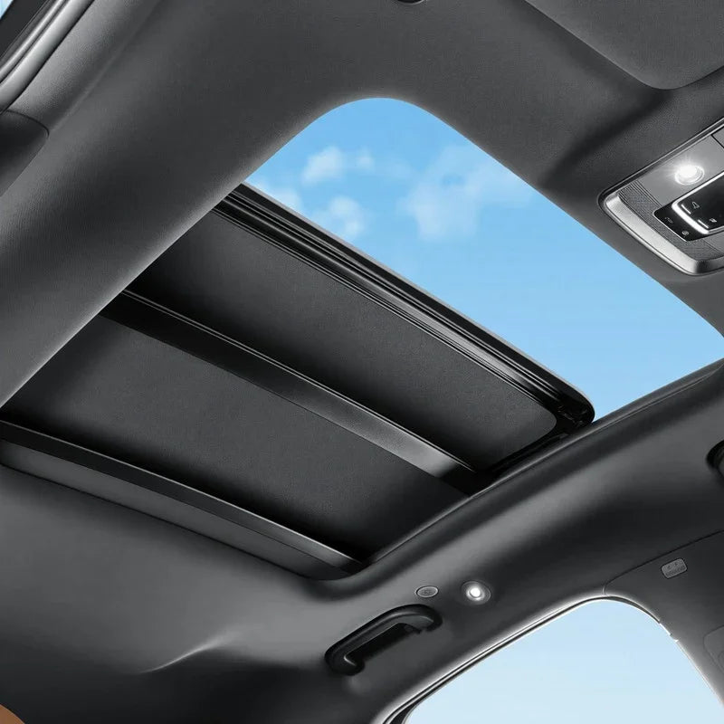 Black fabric sunroof cover installed in a car ceiling under a blue sky.