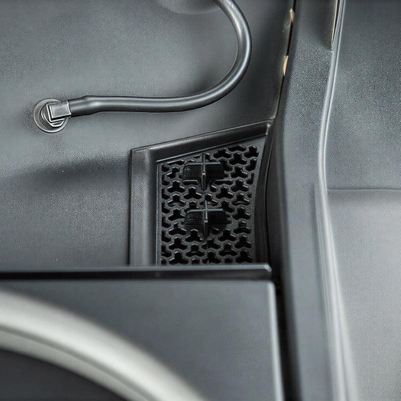 Black textured plastic door pocket storage compartment with a honeycomb mesh pattern.