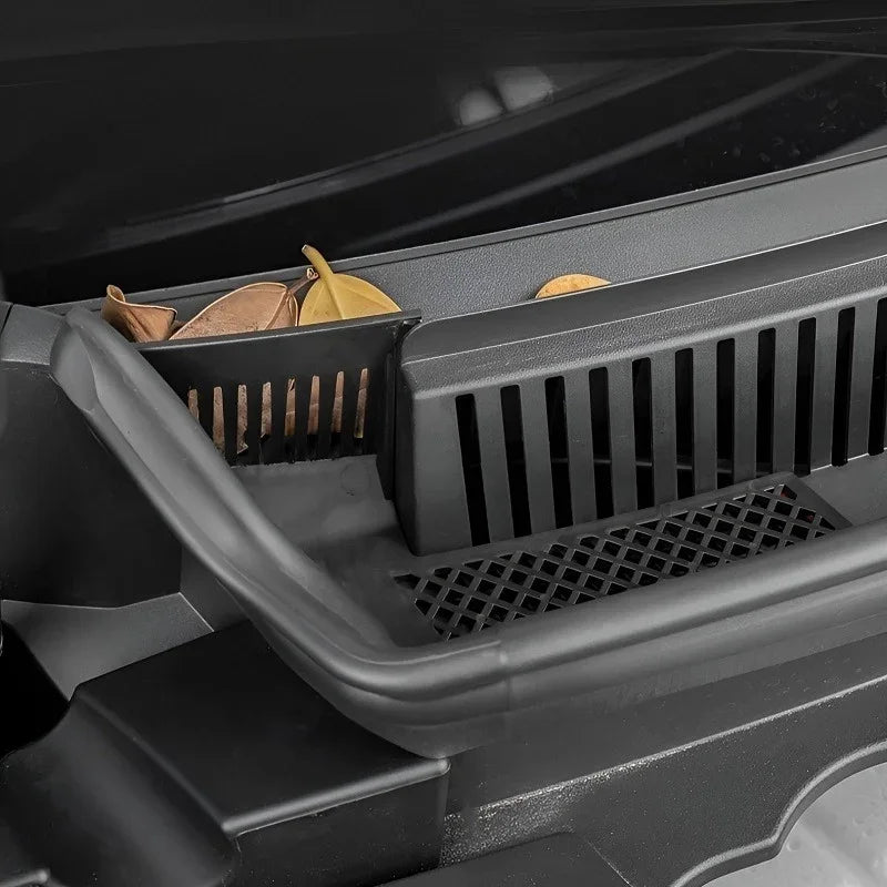 Close-up of a durable black plastic car accessory tray collecting autumn leaves.