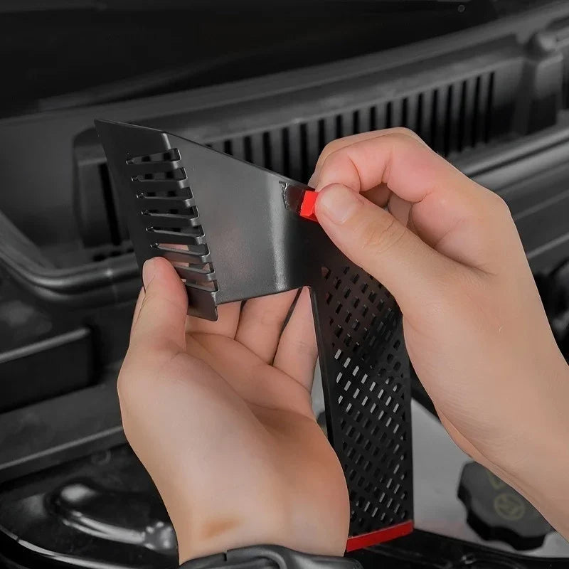 Black perforated protective trim piece with red adhesive backing being installed in a car.