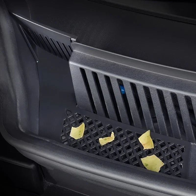 Black textured plastic car interior storage tray with food crumbs