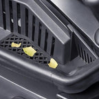 Close-up of a black durable plastic car floor mat with food crumbs on its textured surface.