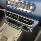 Blue dashboard featuring black air vents with orange accents and a carbon fiber texture wireless charger.