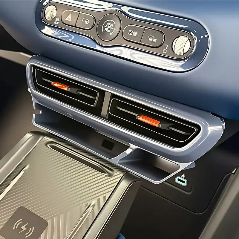 Blue dashboard featuring black air vents with orange accents and a carbon fiber texture wireless charger.