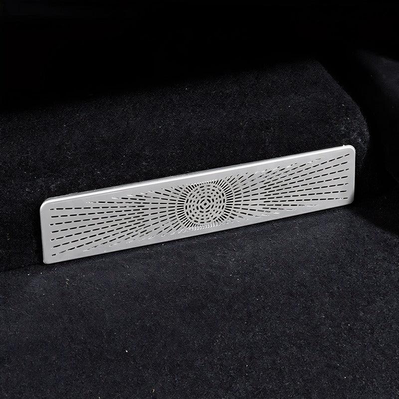 Silver metallic car interior trim piece with a precision laser-cut radial pattern on black carpet.