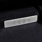 Silver metallic car interior trim piece with a precision laser-cut radial pattern on black carpet.