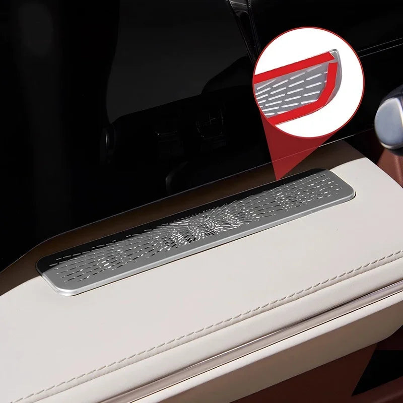Silver textured metallic trim plate with intricate embossed patterns on a cream leather armrest.