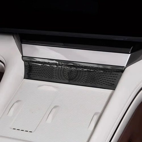 Close-up of a sleek black patterned console trim piece installed in a white luxury car interior.