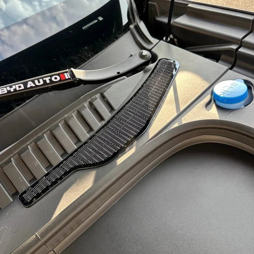 Black carbon fiber texture car accessory panel installed on a vehicle cowl.