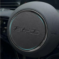 Black textured leather steering wheel cover with a sleek silver trim and subtle blue LED ring.