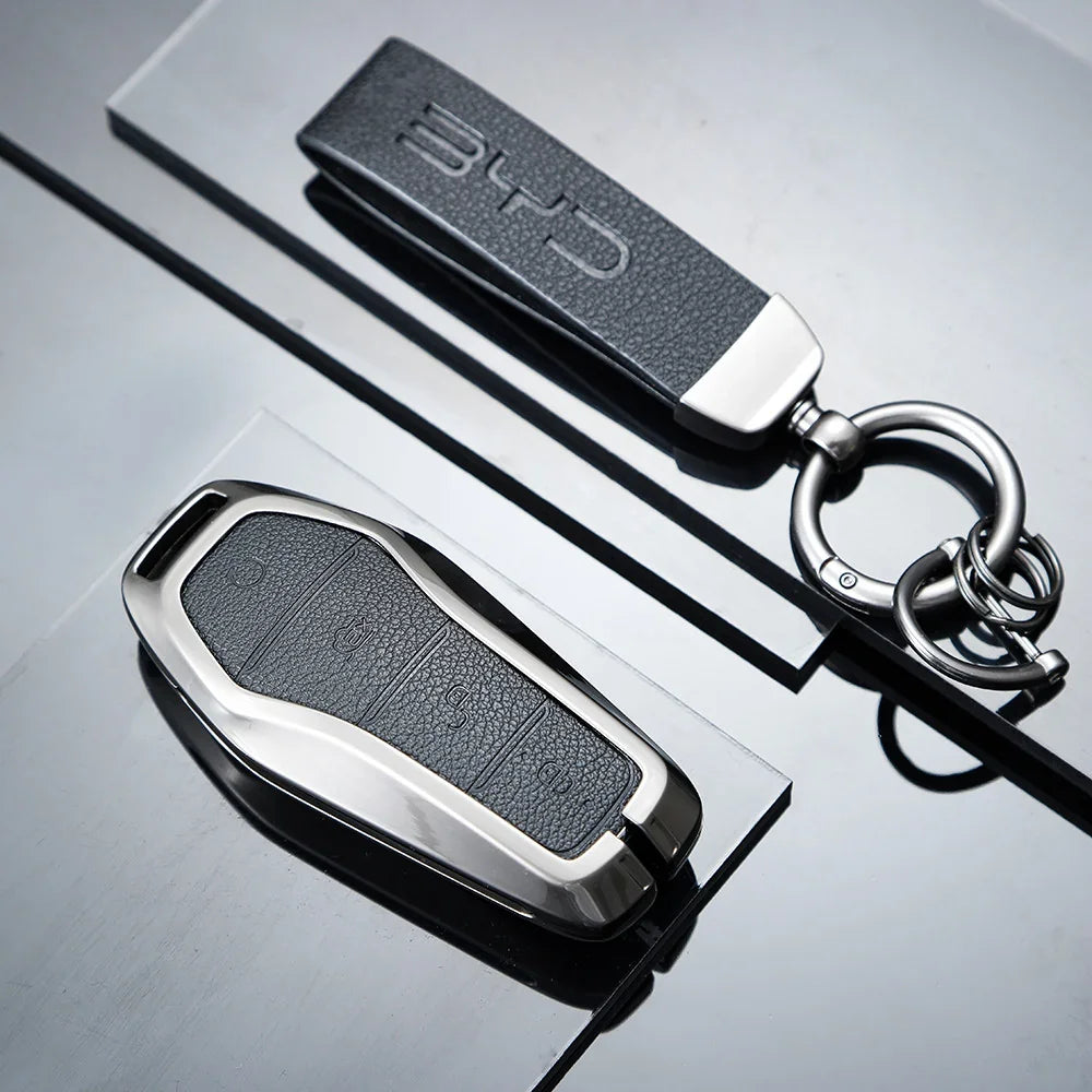 Black textured leather BYD car key cover with sleek metallic silver trim and keyring.