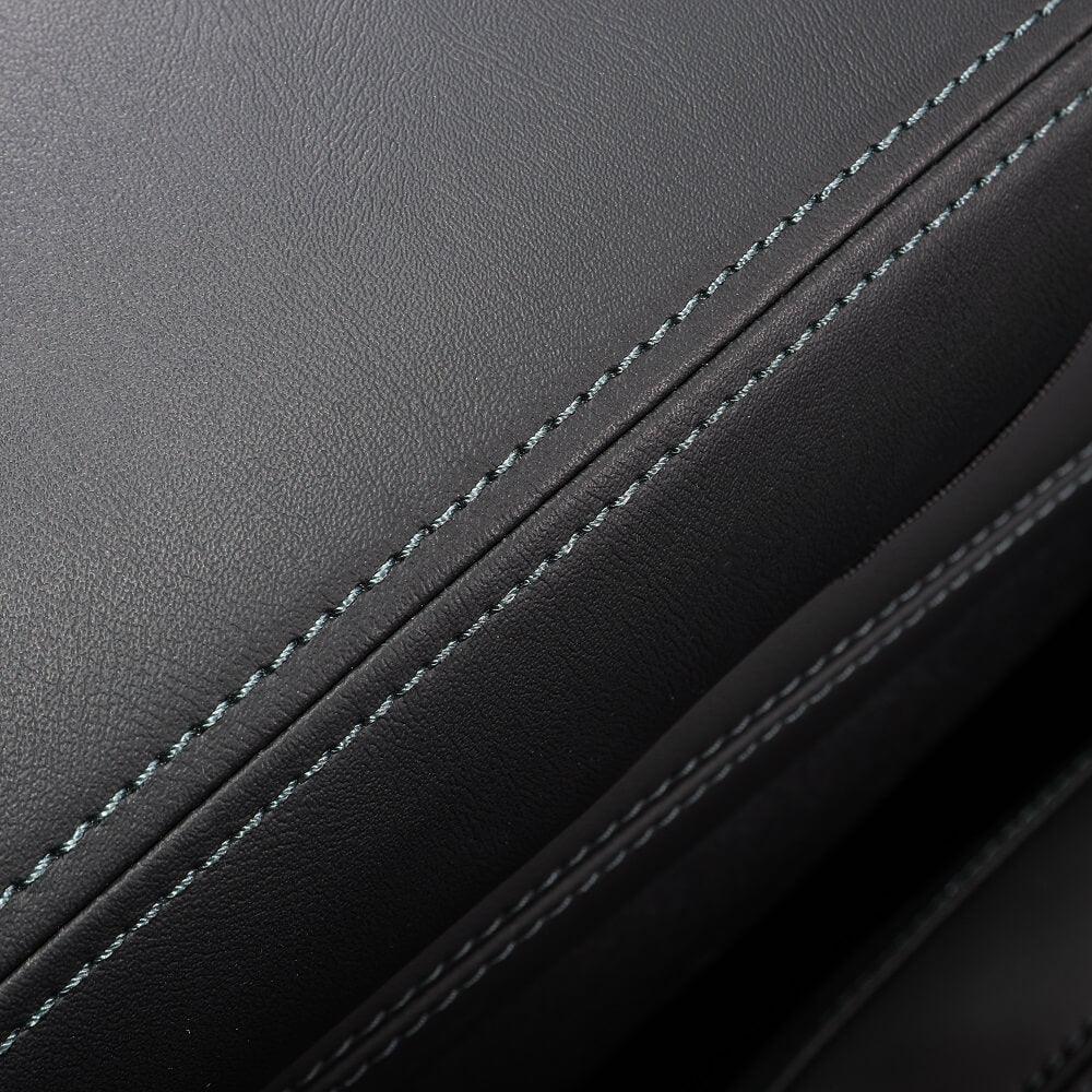 Close-up of premium black leather upholstery with precision blue contrast stitching.