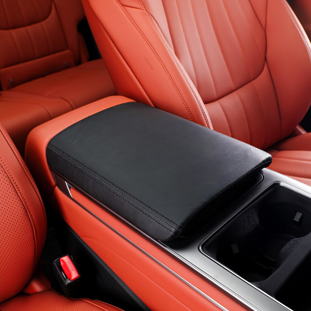 Black leather center console armrest cover installed on red car interior seats.