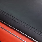 Close-up of premium black leather seat upholstery with precision stitching and orange trim.