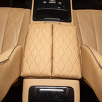 Tan leather center armrest cover with luxury diamond stitching for car interior.