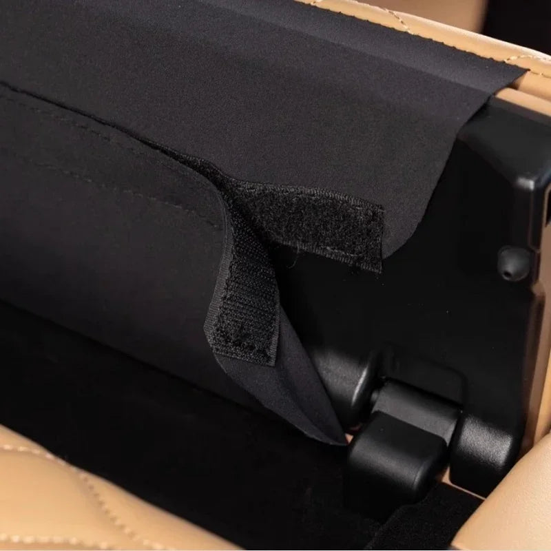 Close-up of a black durable fabric storage pocket with a velcro closure for a car seat.