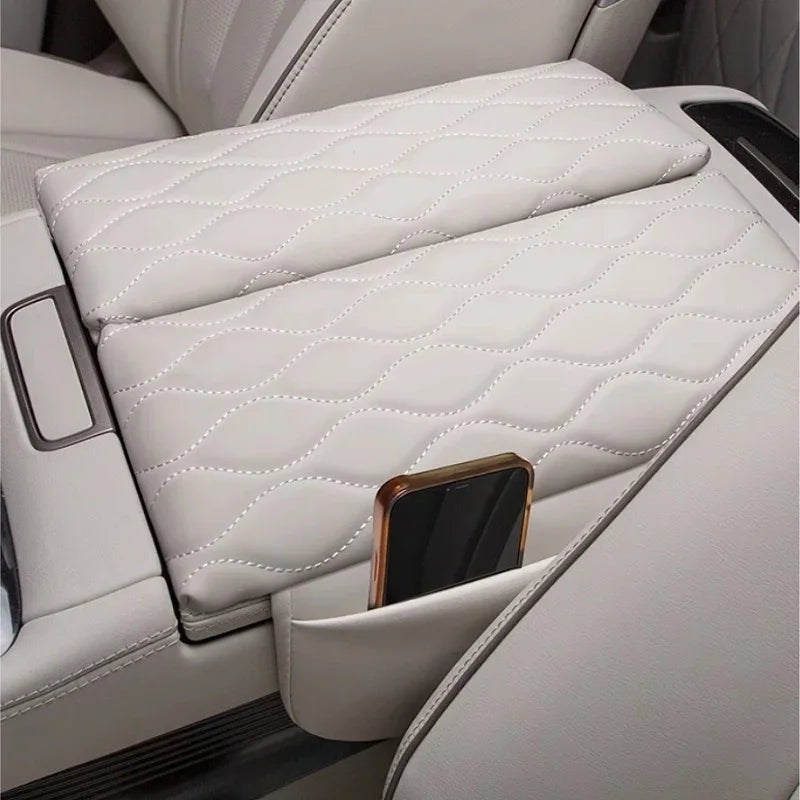 Diamond-stitched cream leather center console armrest cover with integrated phone storage pocket.