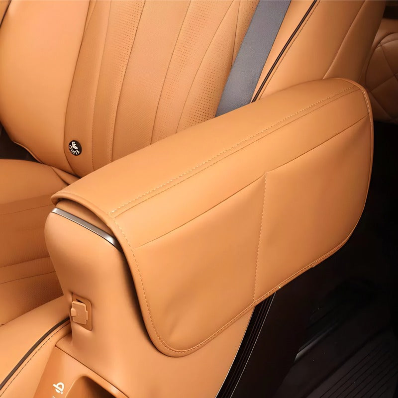 Tan leather car center console armrest cover with premium stitching and soft texture.