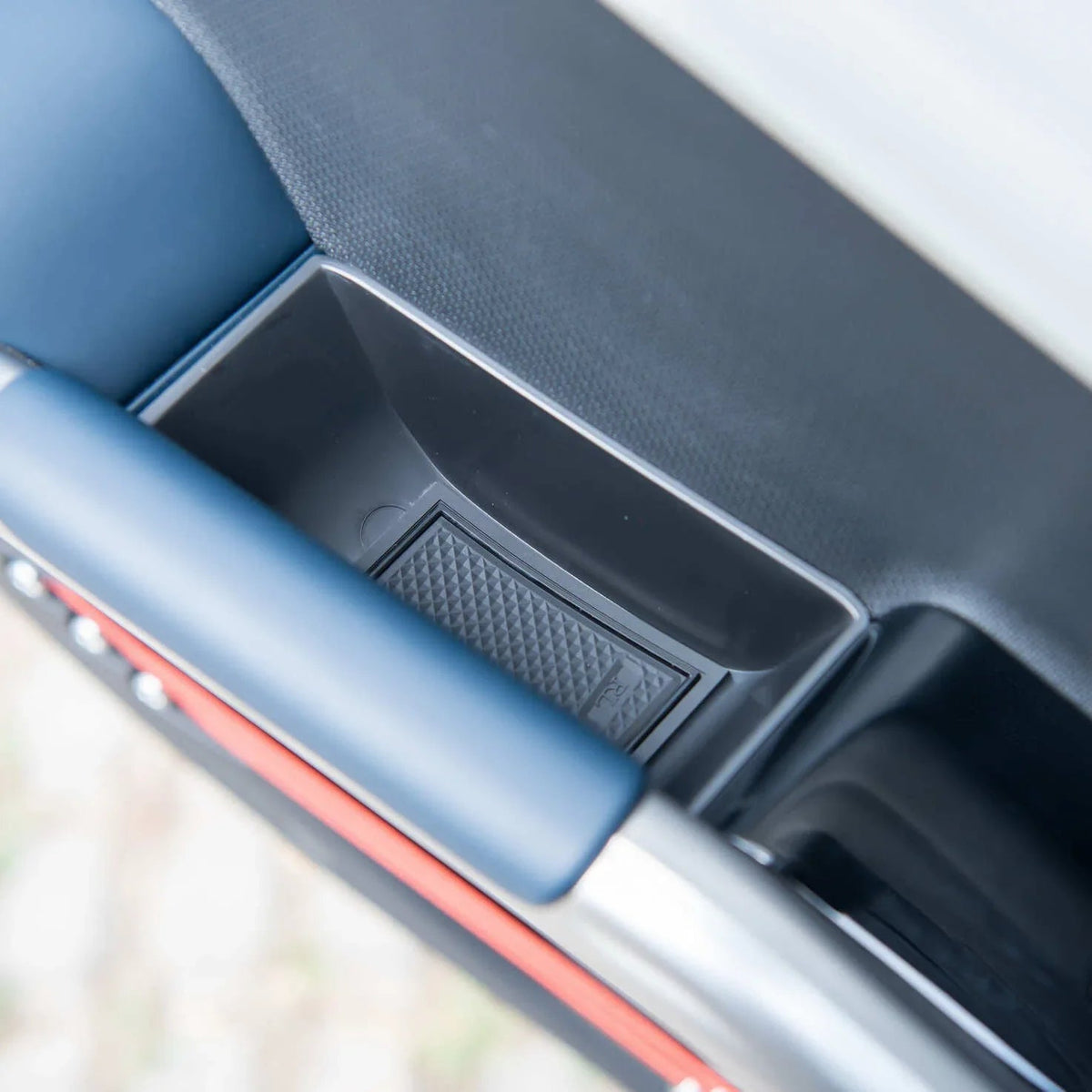 Black textured door pocket storage compartment in a premium blue and silver car interior.
