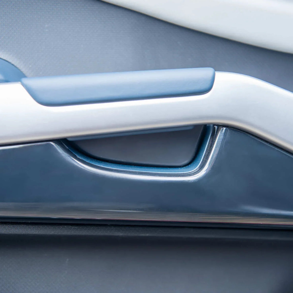 Sleek silver and navy blue interior door handle trim with a smooth matte finish.