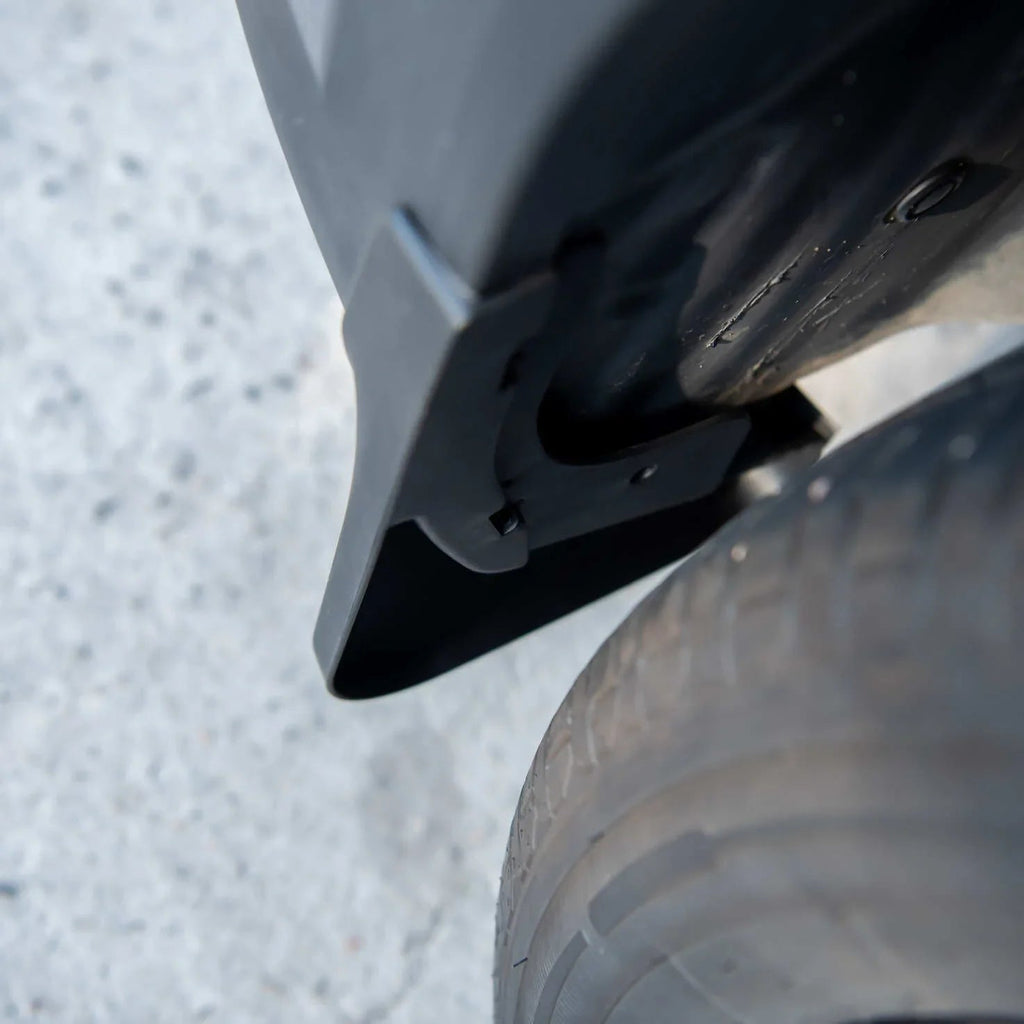 Black durable matte plastic mud flap installed on a vehicle wheel arch for protection.