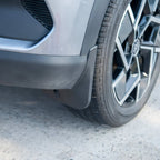 Durable matte black rubber mud flap installed behind the front wheel of a grey car.
