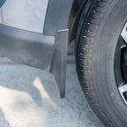 Black durable rubber mud flap installed on the side of a grey car near the tire.